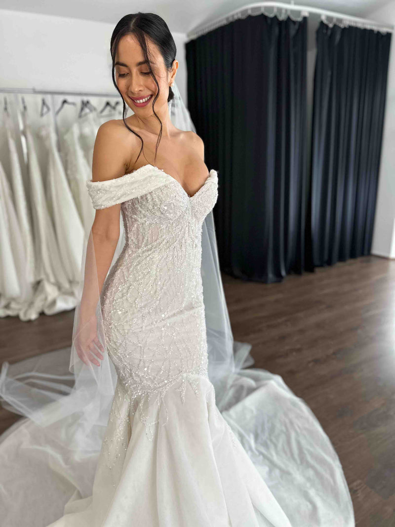 bride smiling in her mermaid wedding gown in front of black curtains