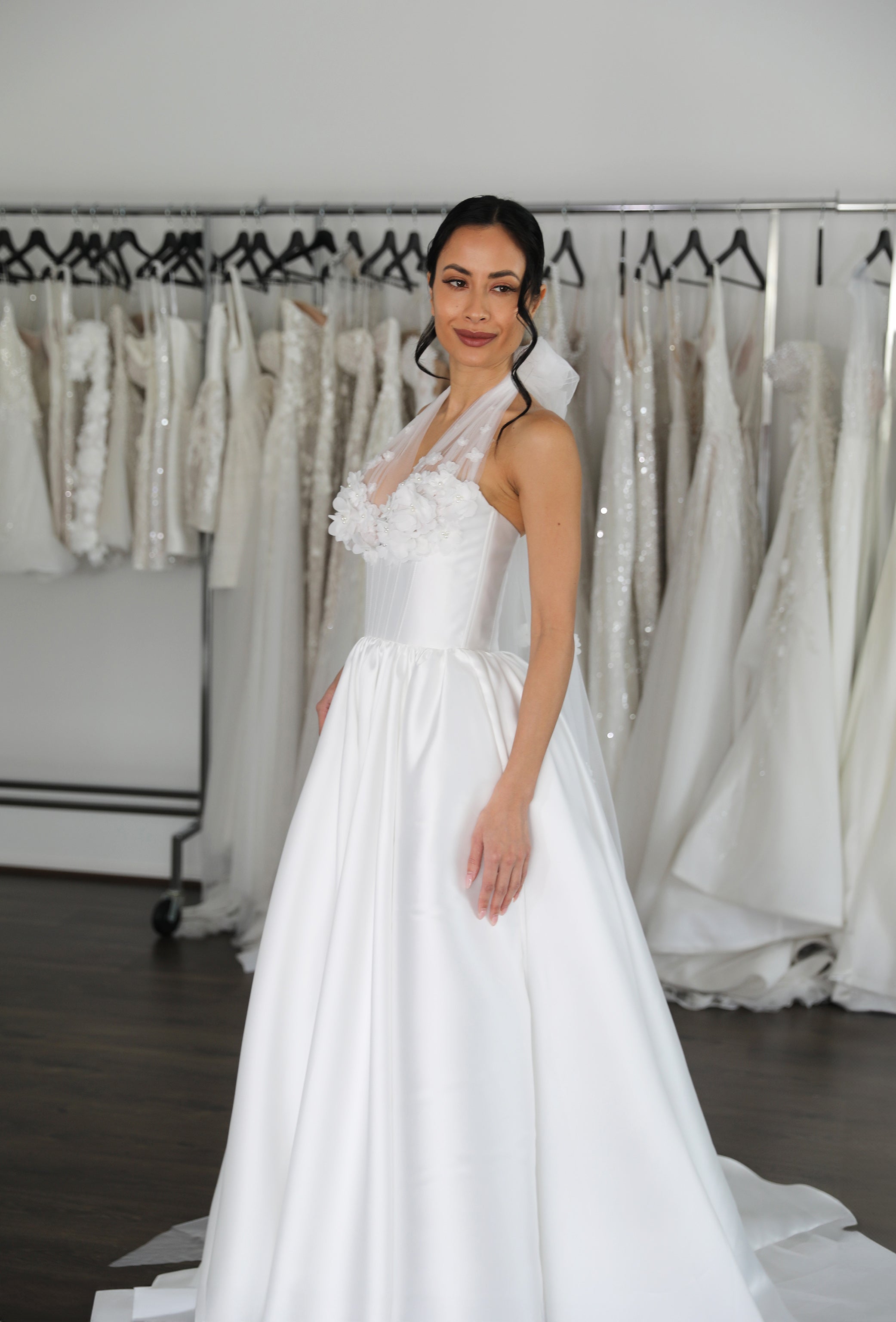 bride standing in front of racks of wedding dresses