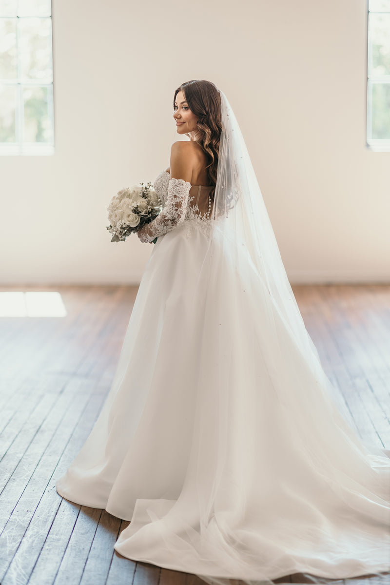 bride walking with her bouquet wearing a wedding dress and outerskirt