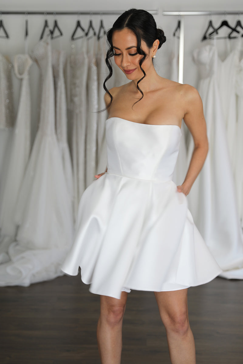 bride wearing mini reception dress with hands in pockets