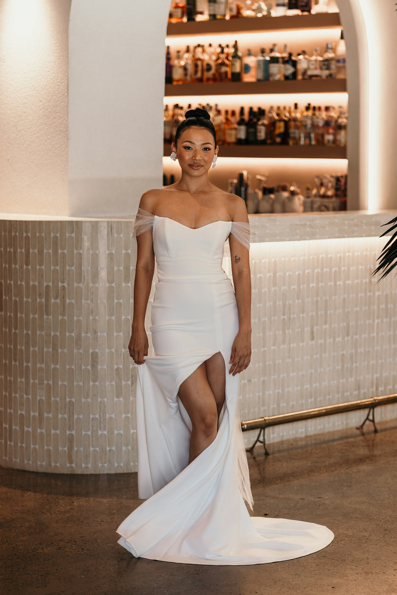 bride wearing off the shoulder bridal gown with thigh high split