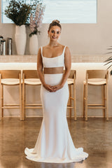 bride with clasped hands in white crepe wedding dress with illusion front pane