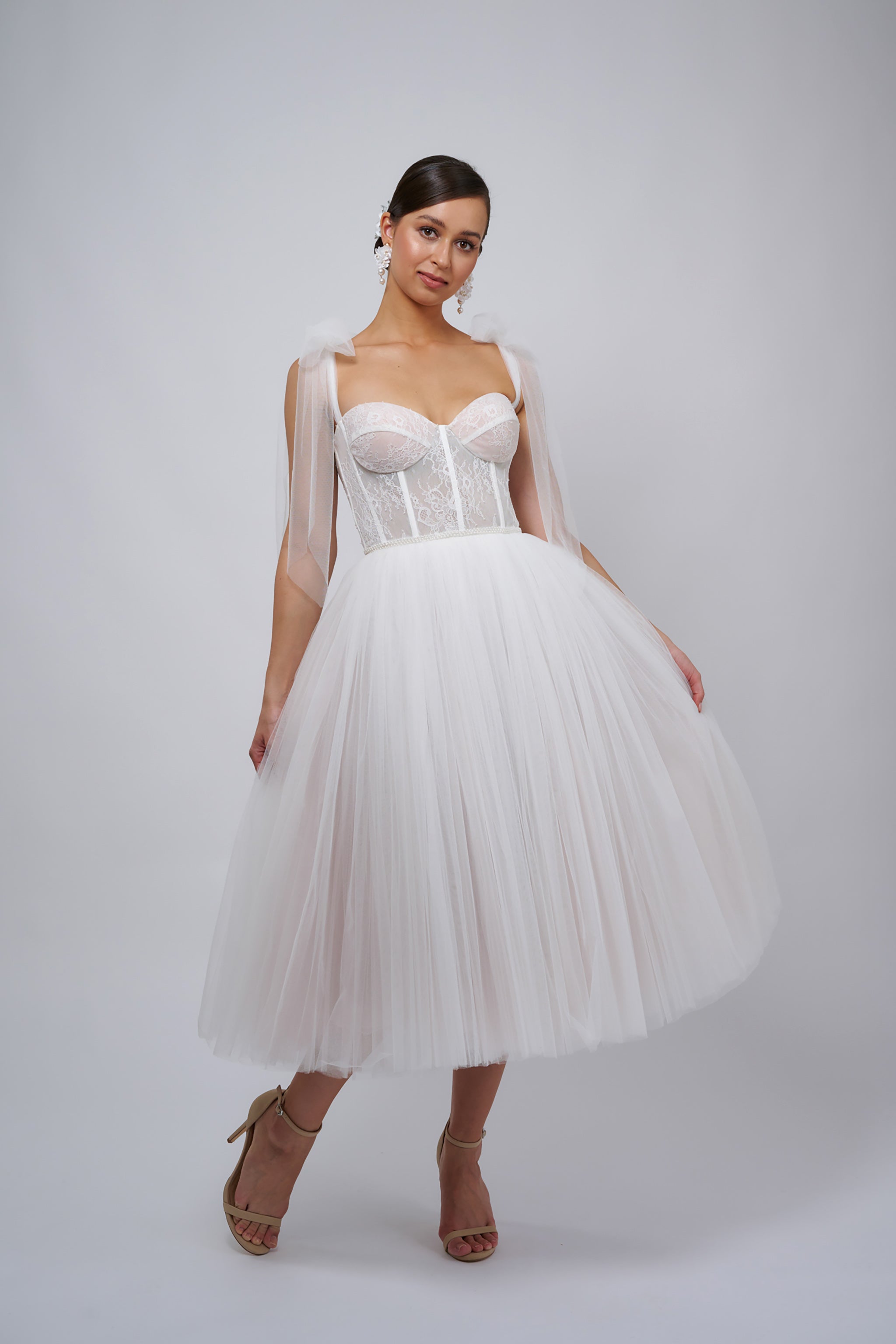 brunette woman wearing corsette wedding dress with bow tie shoulder straps and flowing tulle skirt