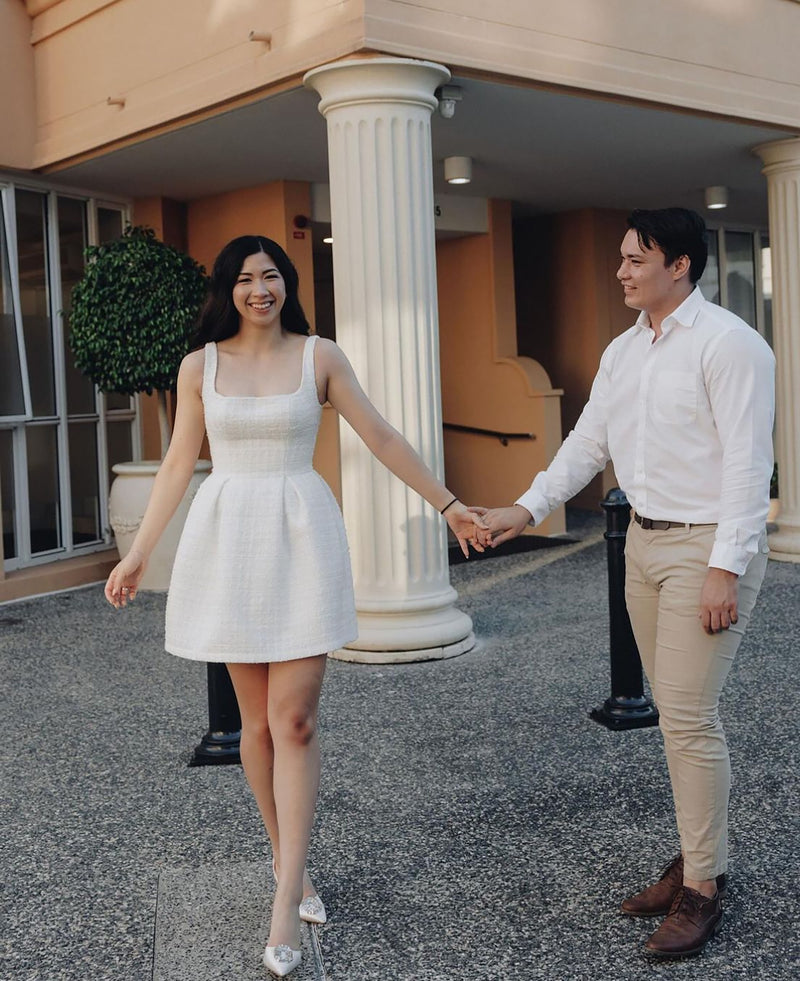 couple holding hands in front of marble pillar