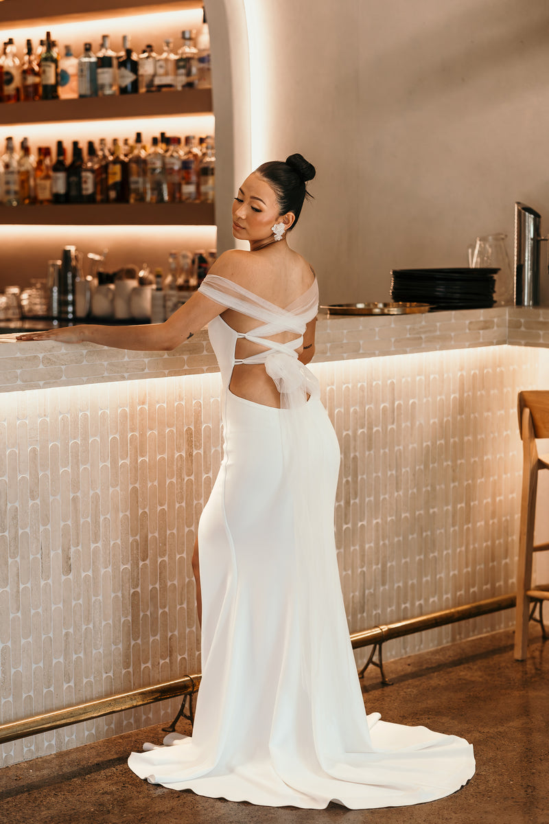 cross back tie up wedding dress on bride standing at bar