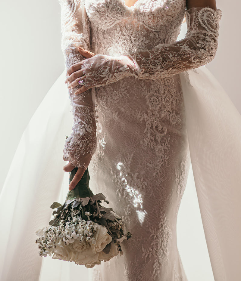 dreamy lace bridal glove matching wedding dress on bride holding bouquet of white flowers