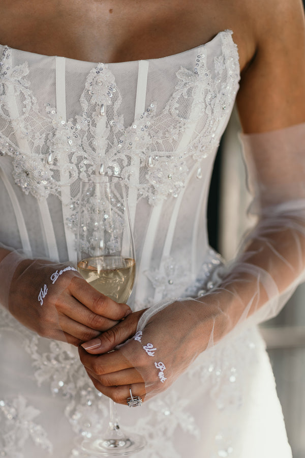 lace embellished bridal corset with embroidered lace gloves holding glass on wine