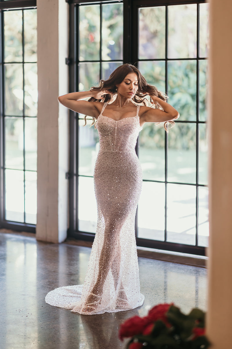 model posing in beaded wedding dress in front of windows