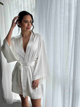 model posing in front of curtains earring white silky bridal robe