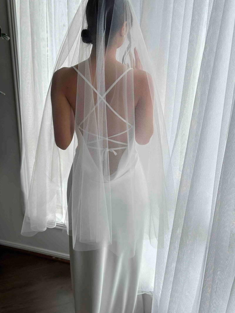 short tulle bridal veil on woman wearing white slip dress