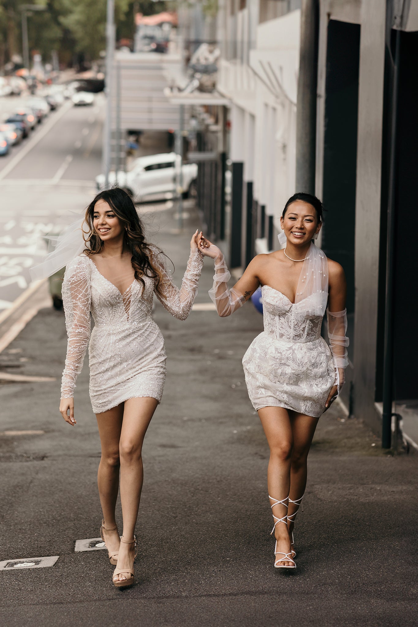 two women hold hands in mini dresses on wedding day