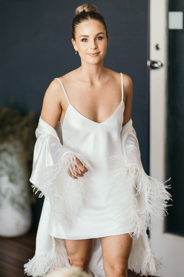 woman in white slip dress with feathery robe hanging off her shoulders