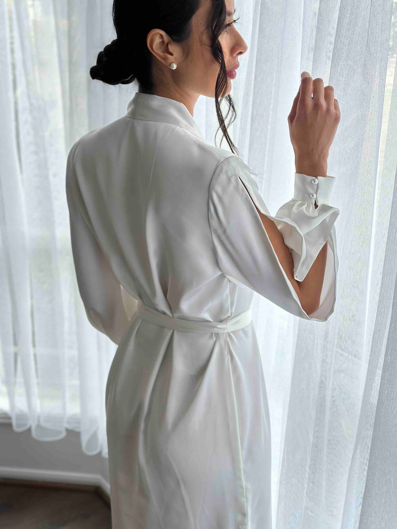 woman peering out window in a dressing robe