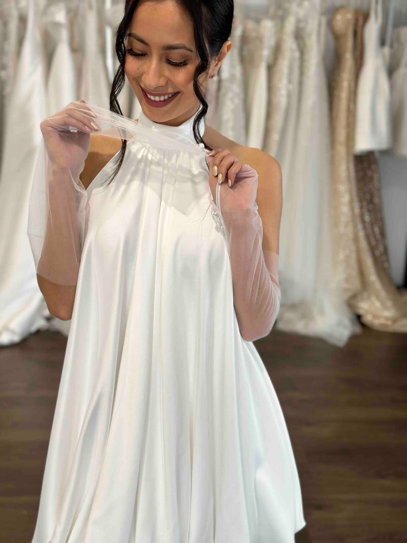 woman playfully holding tulle bridal gloves wearing white dress smiling