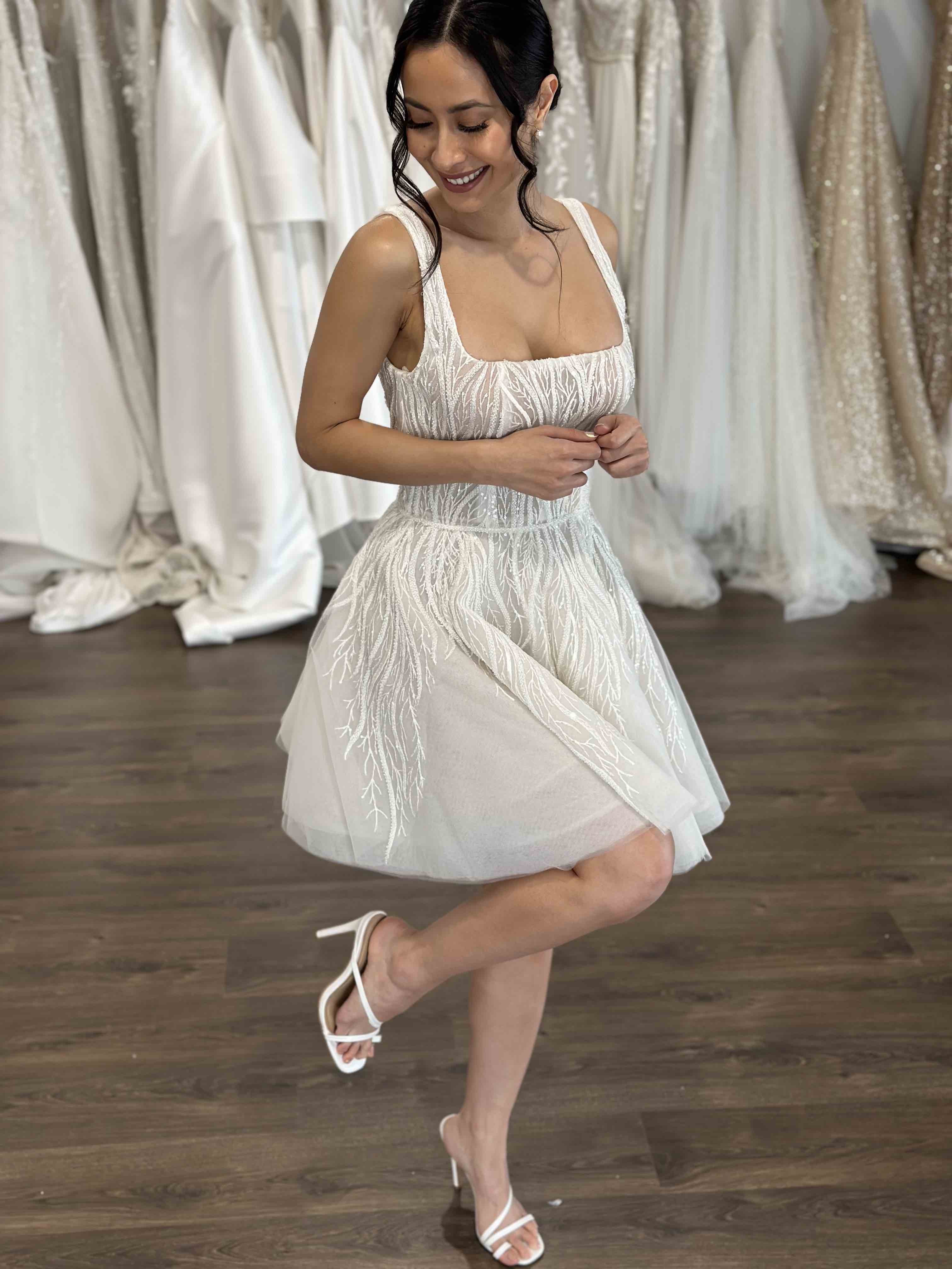 woman posing with leg curved in u-neck wedding mini gown