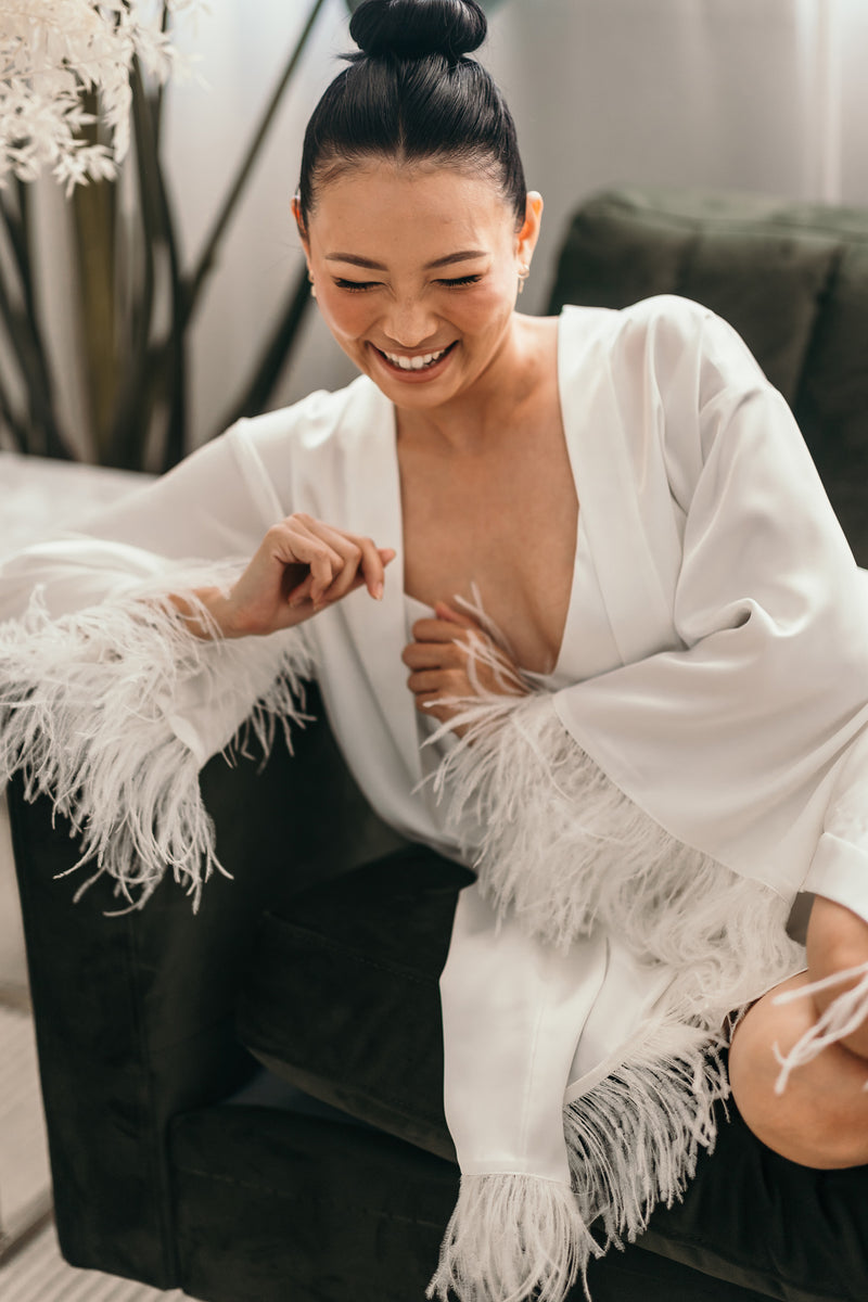 woman smiling in her feather cuffed white robe