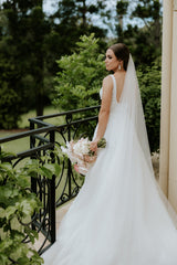 bride in wedding dress with veil and bouquet on balcony