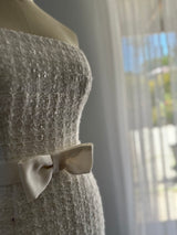close up fabric details of a tweed dress with centre front bow