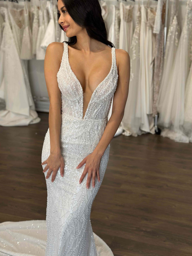 plunging v-neck wedding dress with hands on her thighs posing at bridal studio
