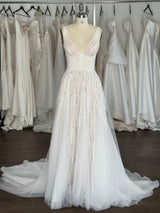 racks of wedding dresses behind a lace wedding dress on a dressform