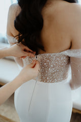 woman hands zipping another woman sip on her wedding dress